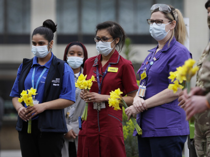 有NHS醫護人員在倫敦的聖托馬斯醫院捧著鮮花默哀。AP圖片