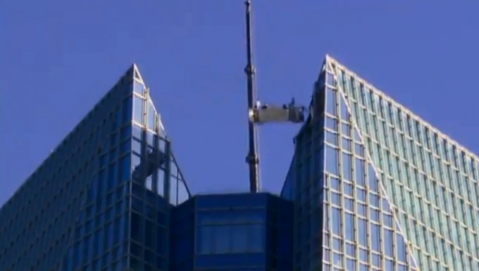 美國兩名洗窗工人進行清潔工作時，起重機突然故障，被吊在50層樓高空上來回擺盪。　網上圖片