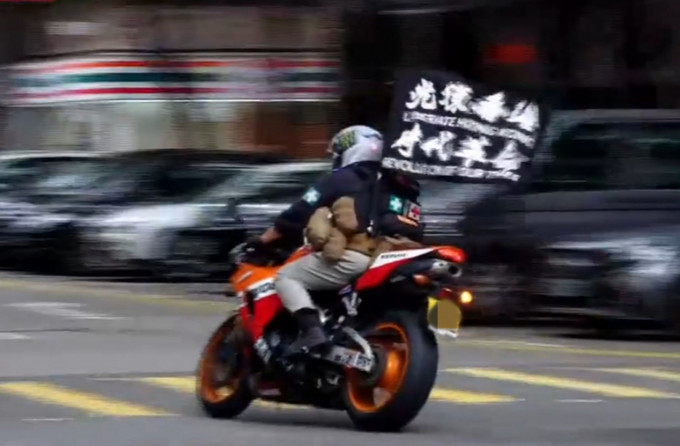 唐英杰于去年七月一日在湾仔驾驶电单车，车上插着两枝写有「光复香港，时代革命」口号的旗帜。资料图片