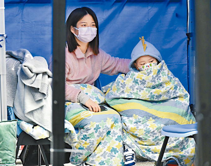 一名母親陪伴小孩在急症室外的帳篷，等待入院消息。