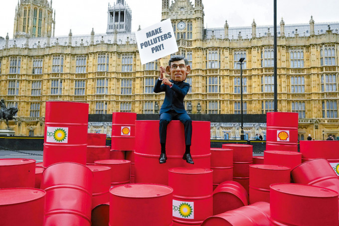 在联合国「气候雄心」峰会前夕，乐施会成员戴起辛伟诚面具，周二在伦敦国会外示威，呼吁英国的石油公司缴纳更多税款。