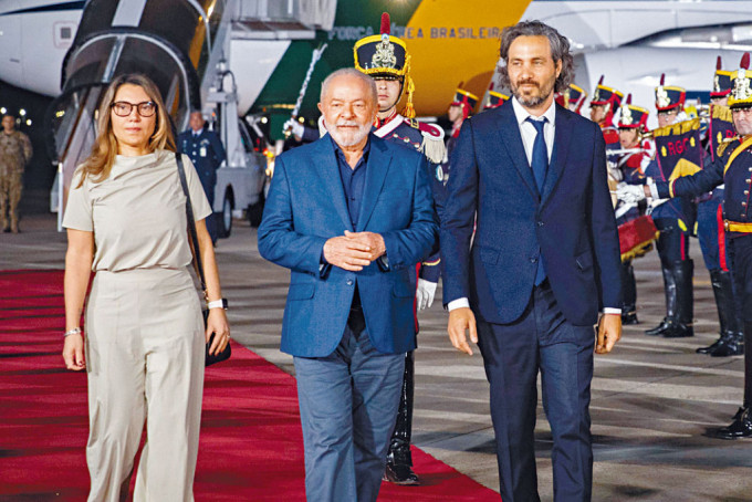 巴西總統盧拉夫婦（左一及二）周日抵達布宜諾斯艾利斯，阿根廷外長卡費羅（右）迎接。