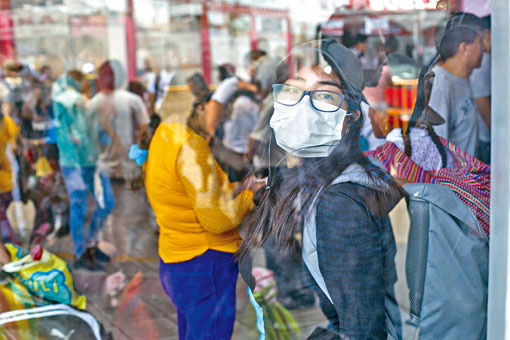 一名戴上口罩的旅客，在利马一个主要巴士站候车。