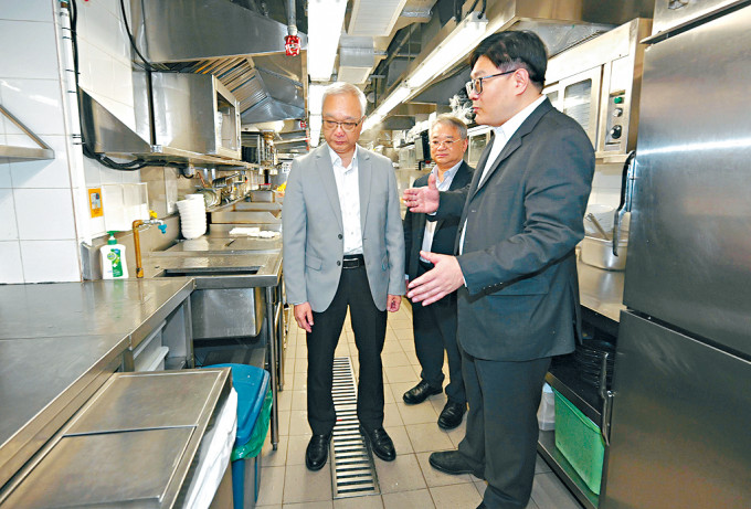 謝展寰和環境保護署署長徐浩光視察連鎖快餐店廚房處理垃圾的過程。