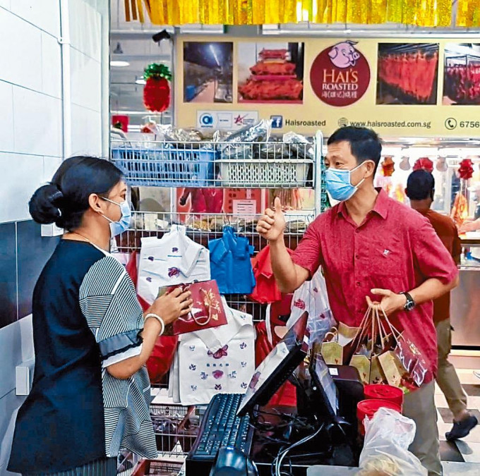 新加坡衞生部长王乙康年初三上载相片，显示他在向商贩派发礼物。