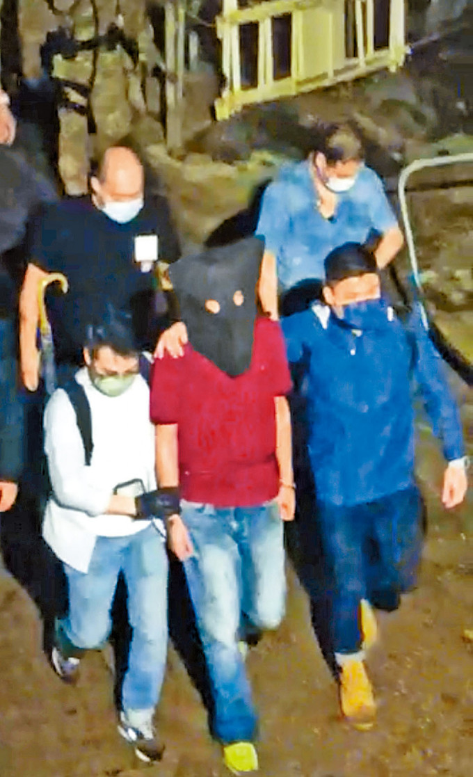 身穿紅衣的疑兇蔡南生，昨晚在南丫島落網後由多名人員押走。