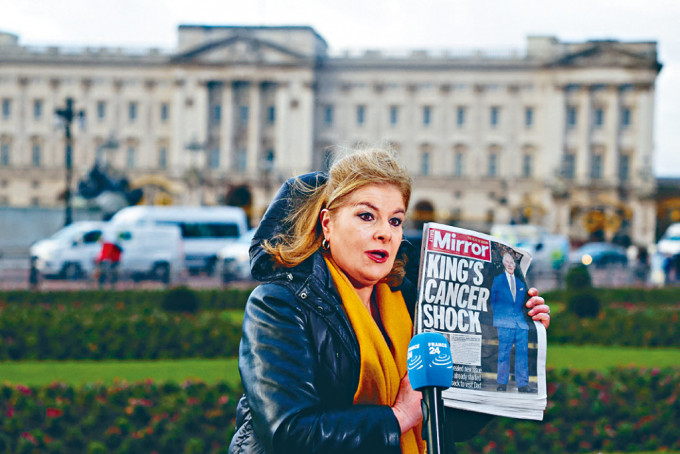 有记者在白金汉宫外采访时，展示《镜报》头版报道英皇患癌。