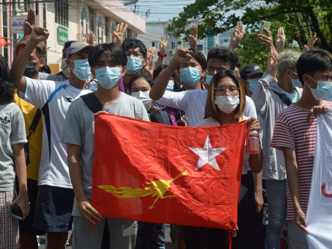反政變抗議者高舉全國民主聯盟黨的旗幟遊行。AP