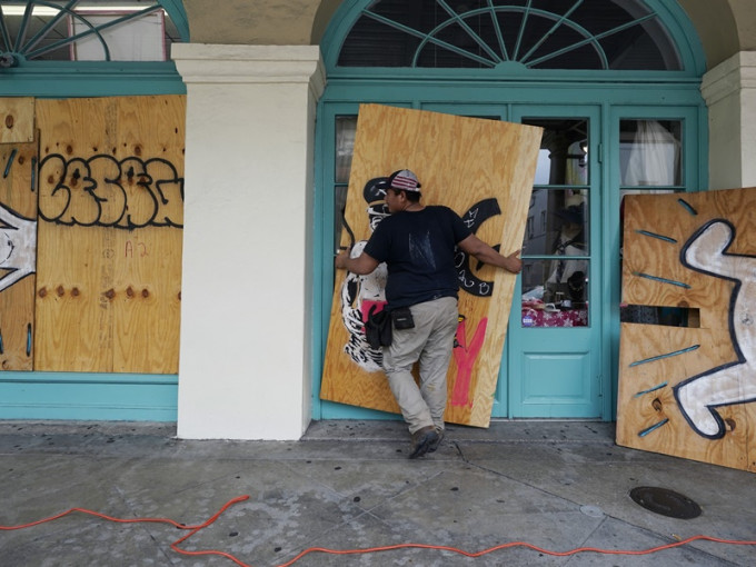 在新奧爾良一名工人在門窗加設防護板防風。AP