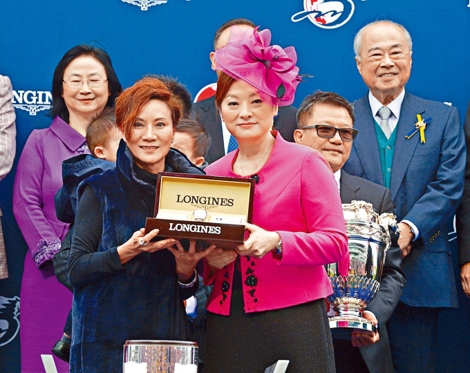 「時時精綵」首度在國際一級賽二千四百米賽事中奪冠當日，王梁秀卿（左）獲贈紀念品。