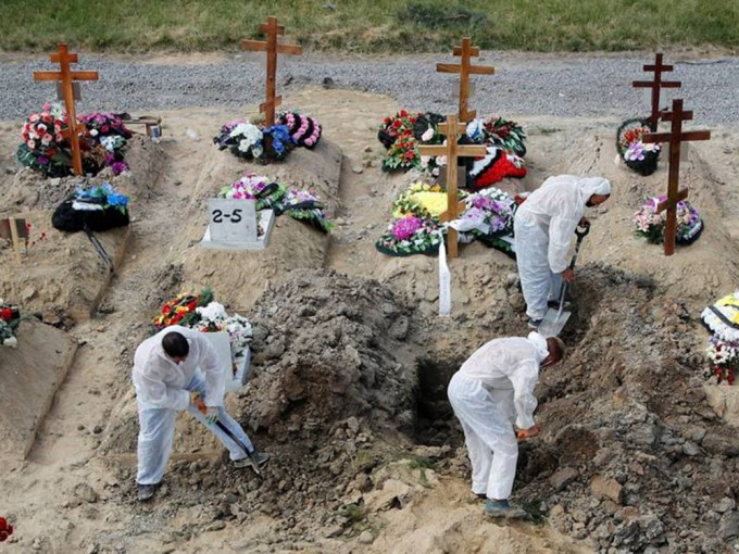 俄罗斯单日新冠死亡人数创新高，圣彼德堡墓园工作人员穿著防护衣掘坟。路透社图片
