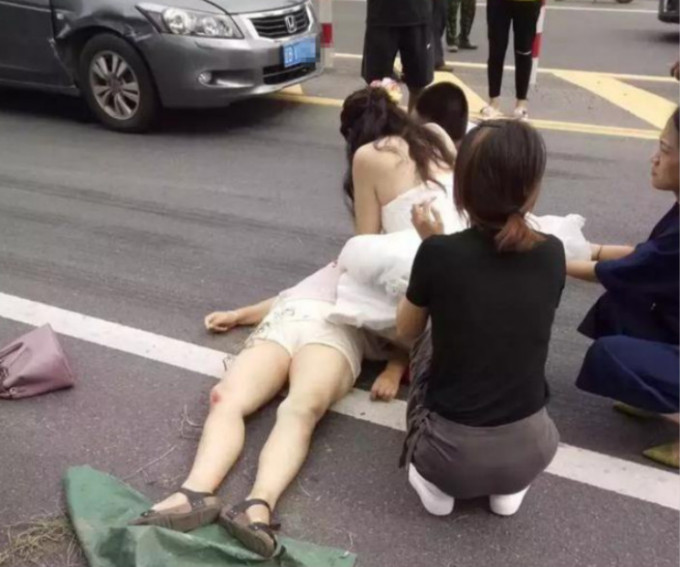 一名身穿婚紗的新娘蹲在地上搶救車禍傷者。網圖