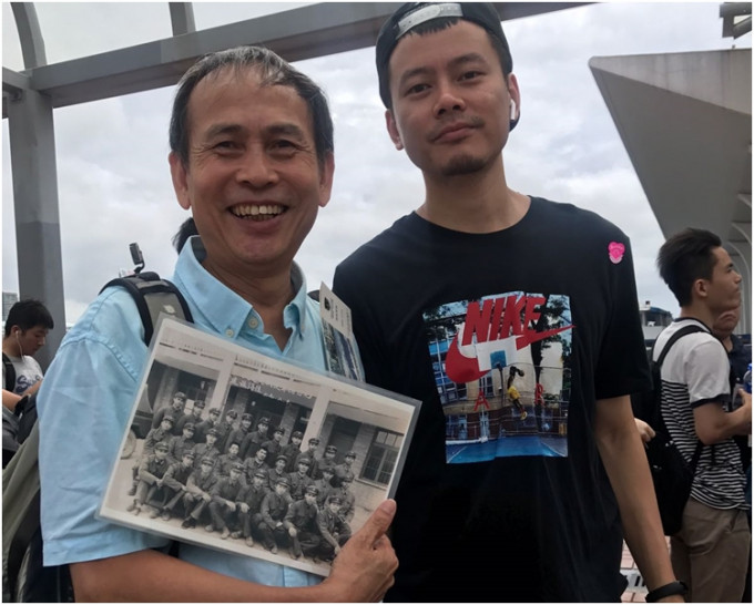 拿著当兵旧相的赖先生（左）期待与解放军拍照，右为其子。