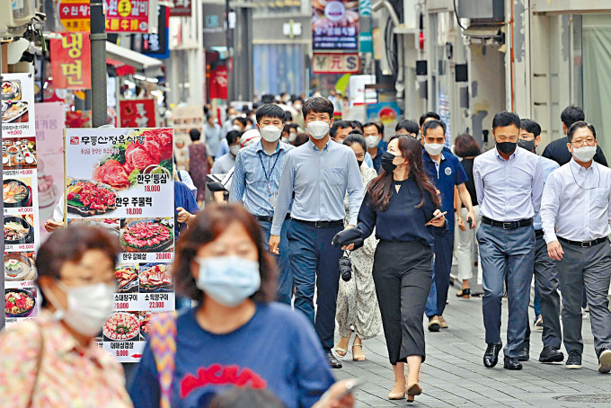 ■首爾著名的明洞購物區昨日人頭湧湧，行人戴上口罩。