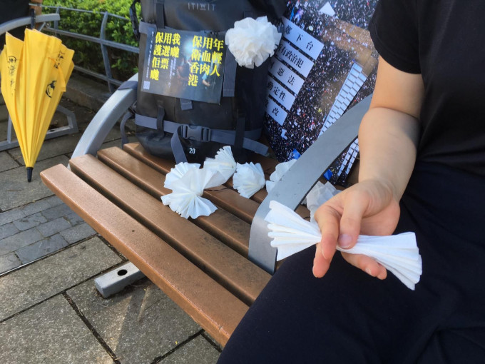洪先生与两名女友人今午自发以纸巾摺成白花。