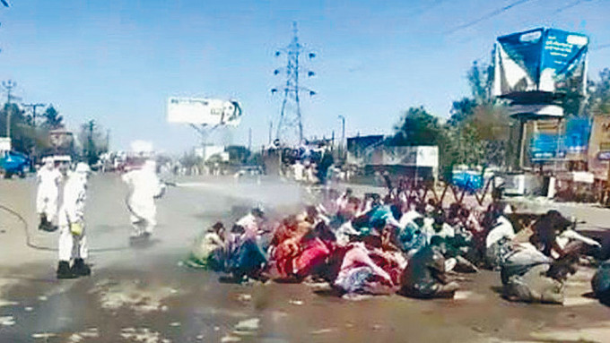 印度一批民工搭车抵达北方邦家乡巴雷利市时，遭当局喷洒液体全身消毒。