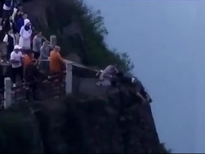 崖上僧人和游客合力将跳崖男子救回。（网图）