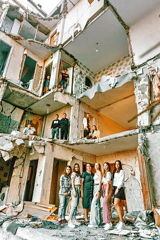 在烏北城市切爾尼戈夫，高中生在被炸毁建築物前拍畢業照。