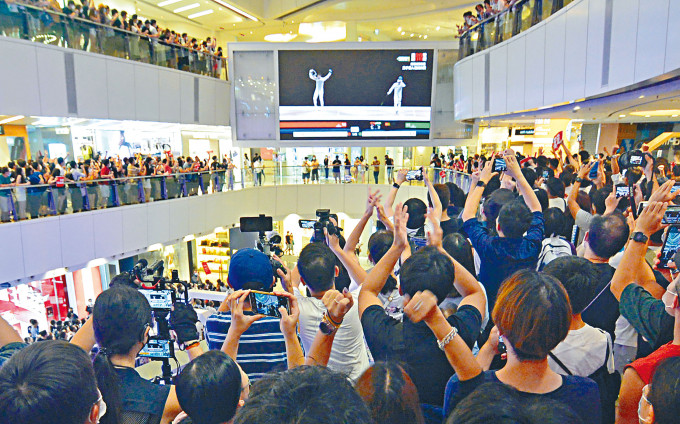 商場各層企滿市民，一同見證香港隊今屆奧運第一金的誕生。