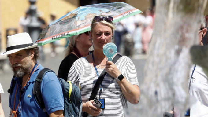 一名女子在羅馬納沃納廣場吹小風扇消暑。 路透社