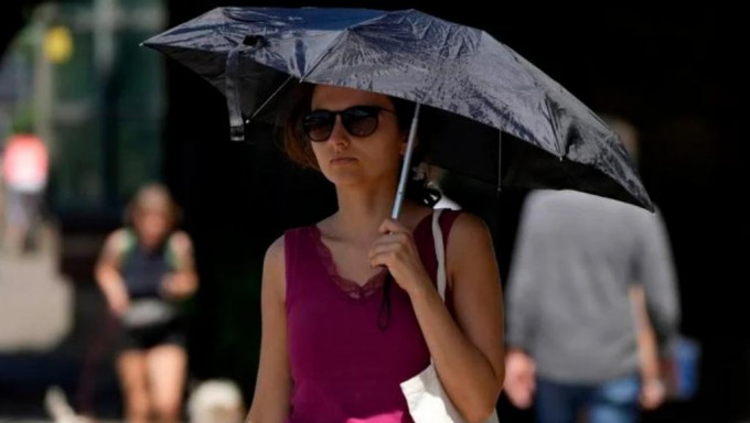 在英国市民外出时都要举伞遮挡烈日。AP