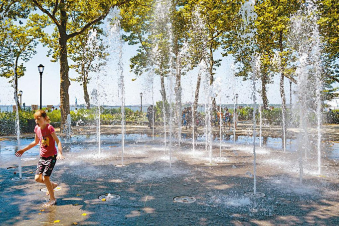 孩子在曼克顿公园的喷水池嬉水消暑。