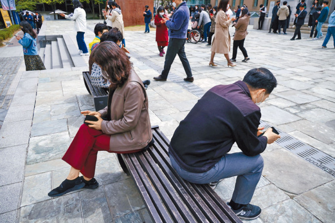 首爾上班族午膳時間在街上看手機。