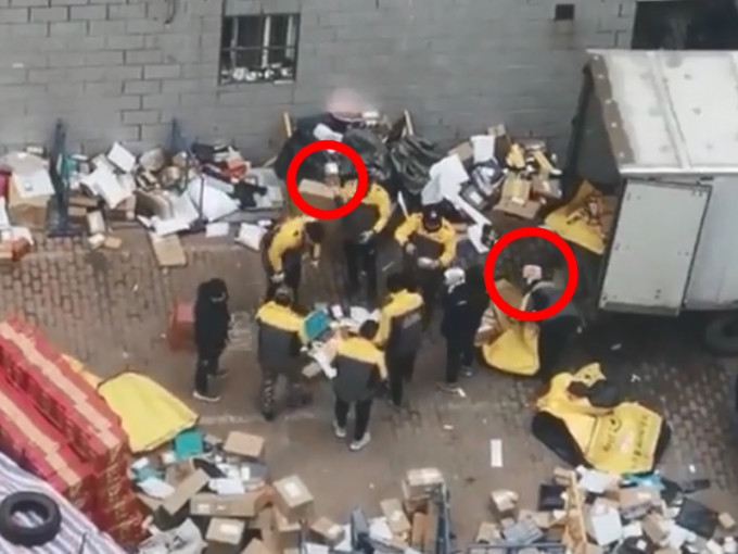 6名穿著制服的快遞員及兩名穿黑衣的工作人員站在原地不動「分揀」包裹。影片截圖