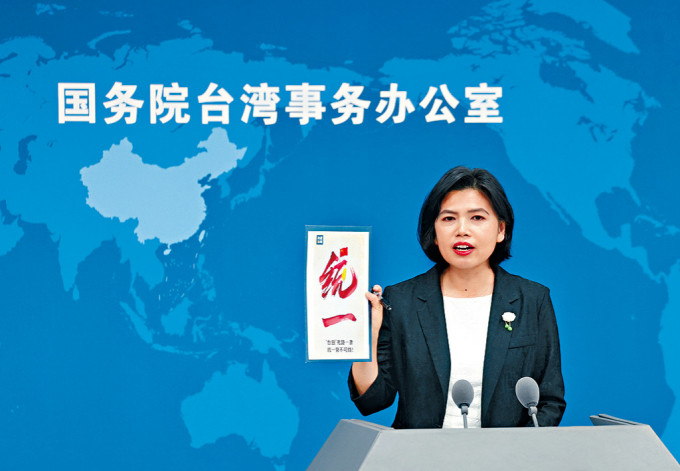 国台办发言人朱凤莲在记者会上拿着「统一」海报。