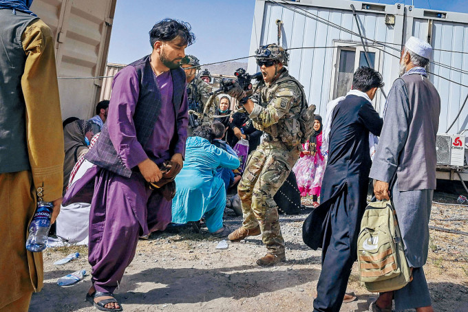 一名美军周一在喀布尔机场举枪指向一名阿富汗人。　