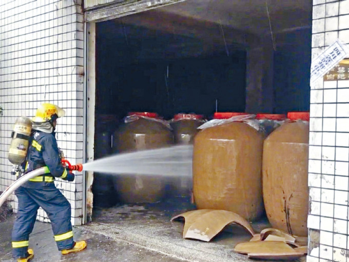 消防人员向储酒罐喷水稀释。