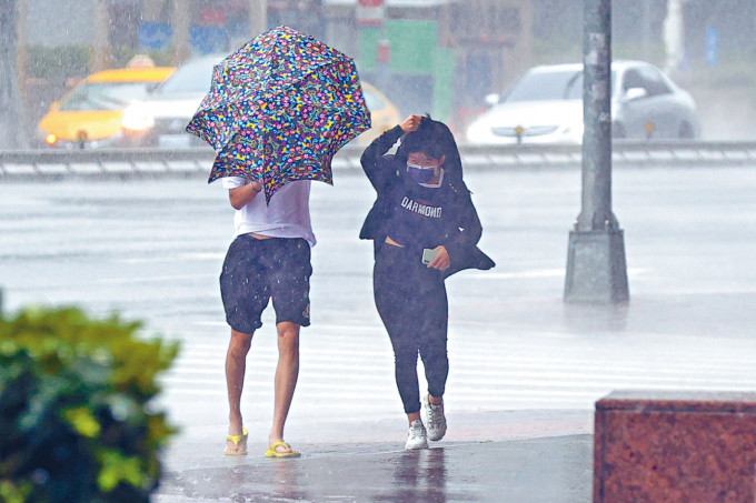 ■台风来袭，台湾民众冒着风雨出门。