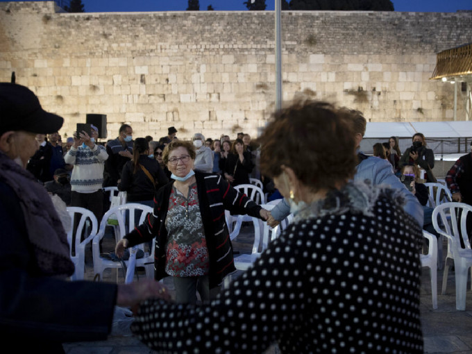 以色列昨日（11月30日）起庆祝光明节，部分人除口罩牵手跳舞。（美联社）