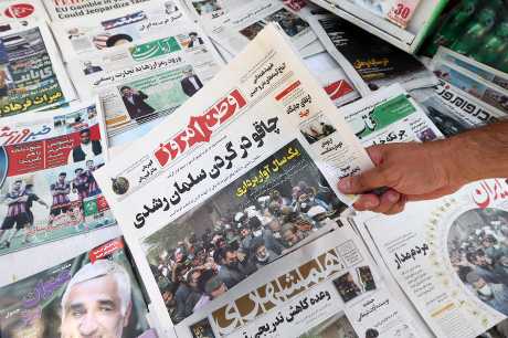 伊朗首都德黑兰一男子周六展示当地报章，其头版标题用波斯语写着「拉什迪脖子上的刀」。