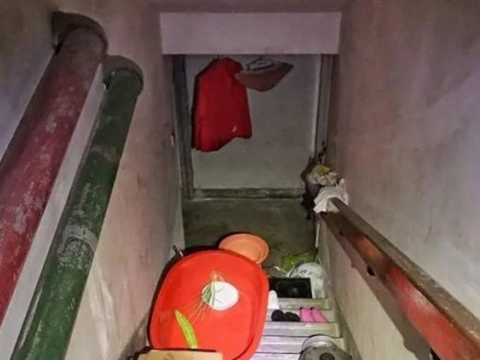 上海一大廈的地下室被佔用並僭建作板間房，樓梯滿住客的雜物。網圖