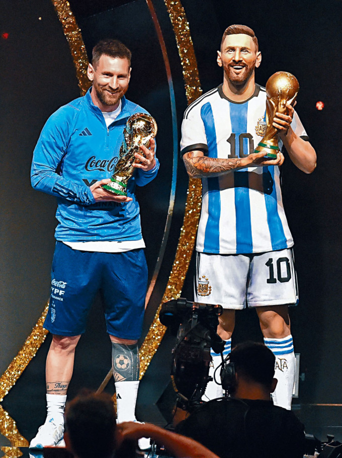 美斯（左）拿着世界盃獎盃仿製品，與1:1的雕像合照。