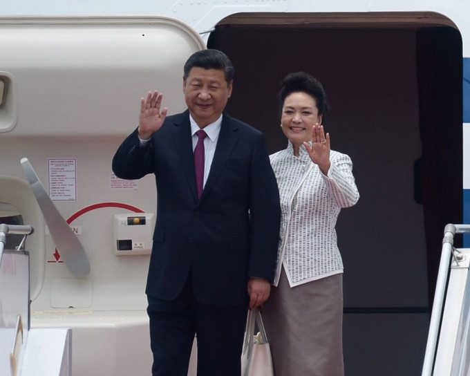 国家主席习近平结上暗红色呔，夫人彭丽媛则穿着银白色衣服，抵达香港。