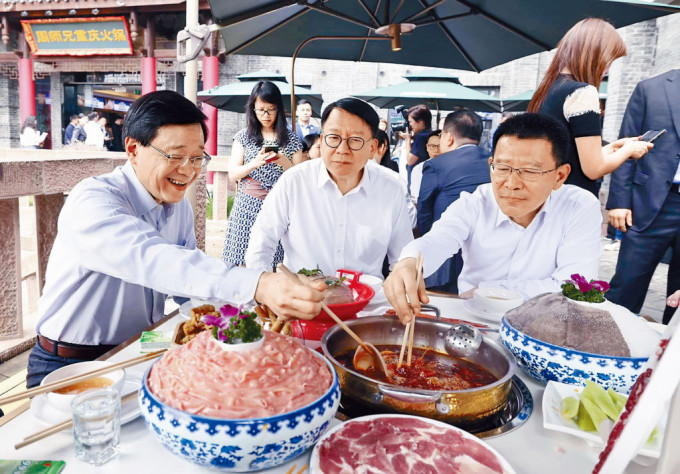 李家超（左）与代表团一行人在磁器口一家火锅店，品尝重庆麻辣火锅。