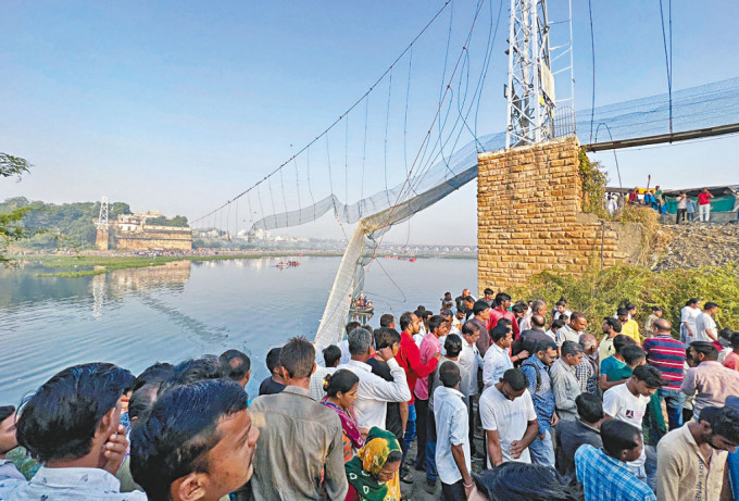 在印度古吉拉特邦莫尔比市，人群周一聚集断裂的吊桥现场。