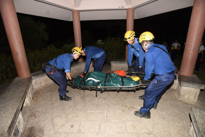 消防員將死者遺體移至公園的涼亭。