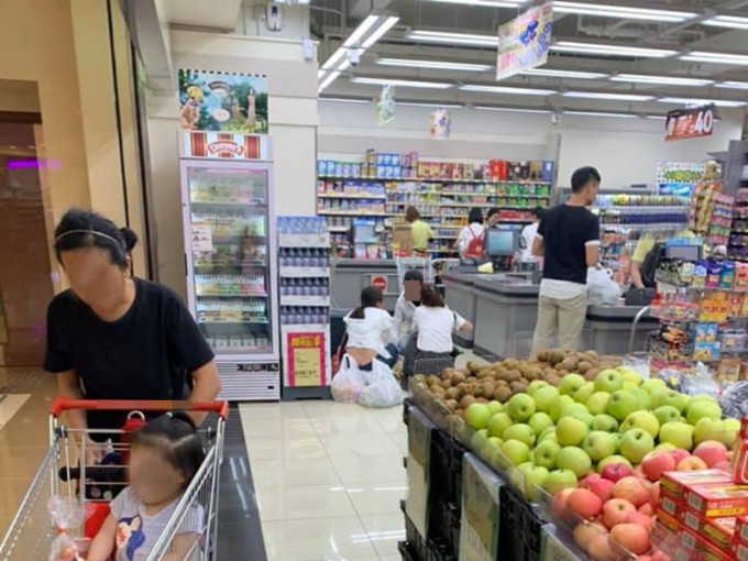 三名女子正蹲在超級市場的收銀機旁邊，圍蹲著吃榴槤。網民OCt Chi圖片