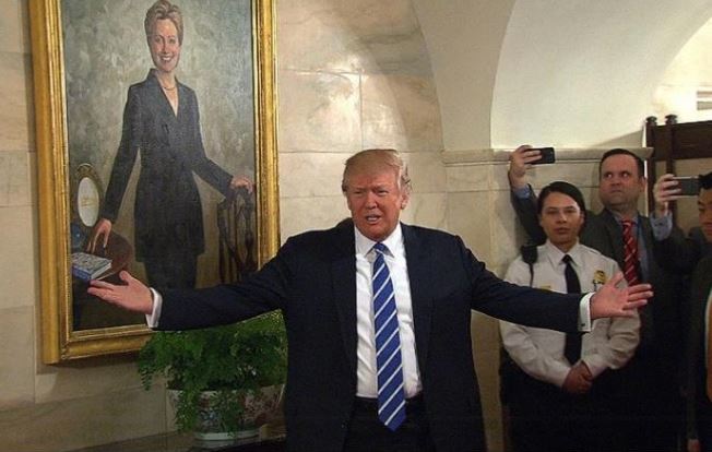 特朗普站在希拉莉肖像畫旁迎接遊客。