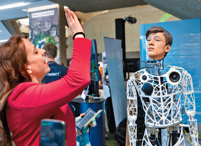 「AI造福人类全球峰会」5月底在日内瓦举行，一名参观者向机械人Captcha挥手。
