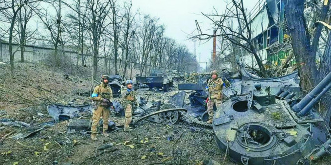 乌克兰国民警衞队亚速营的士兵，在南部港口城市马里乌波尔，检视损毁的俄军坦克。