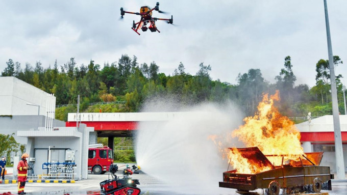 消防人员模拟有车辆起火，示范操控灭火机械人近距离射水扑火，无人机则在高空勘察。
