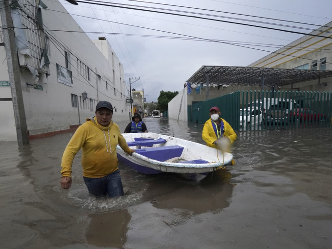 墨西哥中部暴雨引發水災，工作人員帶着小艇離開醫院。AP圖