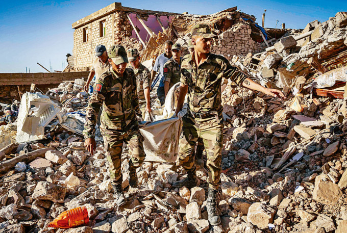 摩洛哥士兵在馬拉喀什附近山村瓦礫堆，挖出一具遺體。