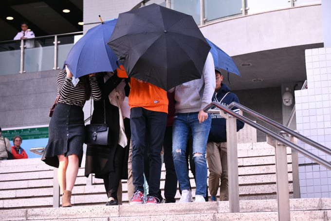 被告离开法庭时被伞阵包围。