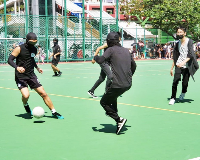 有戴口罩的黑衣人在起步前先在球场内踢波。