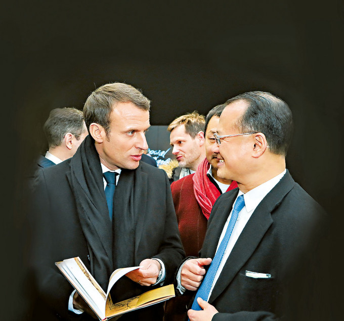 马克龙（左）上任后首次访华，期间与蔡冠深（右）见面，蔡冠深送了一本法文版老子《道德经》给马克龙。